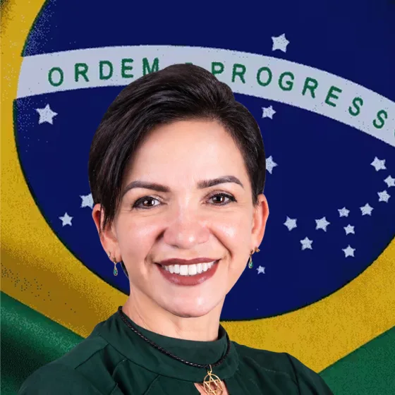 Alê Silva sorrindo diante da bandeira do Brasil